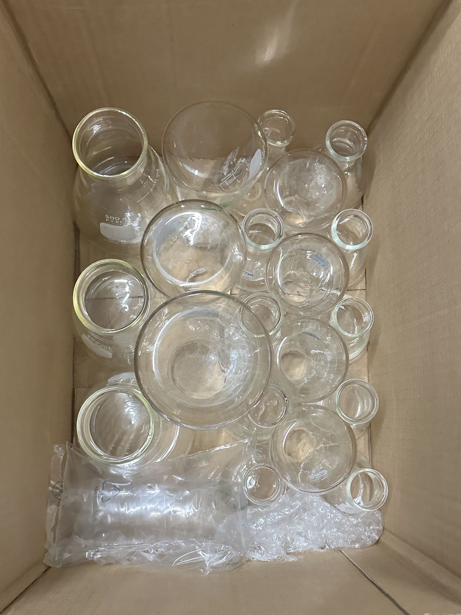 A box of donated glass beakers and flasks being prepared