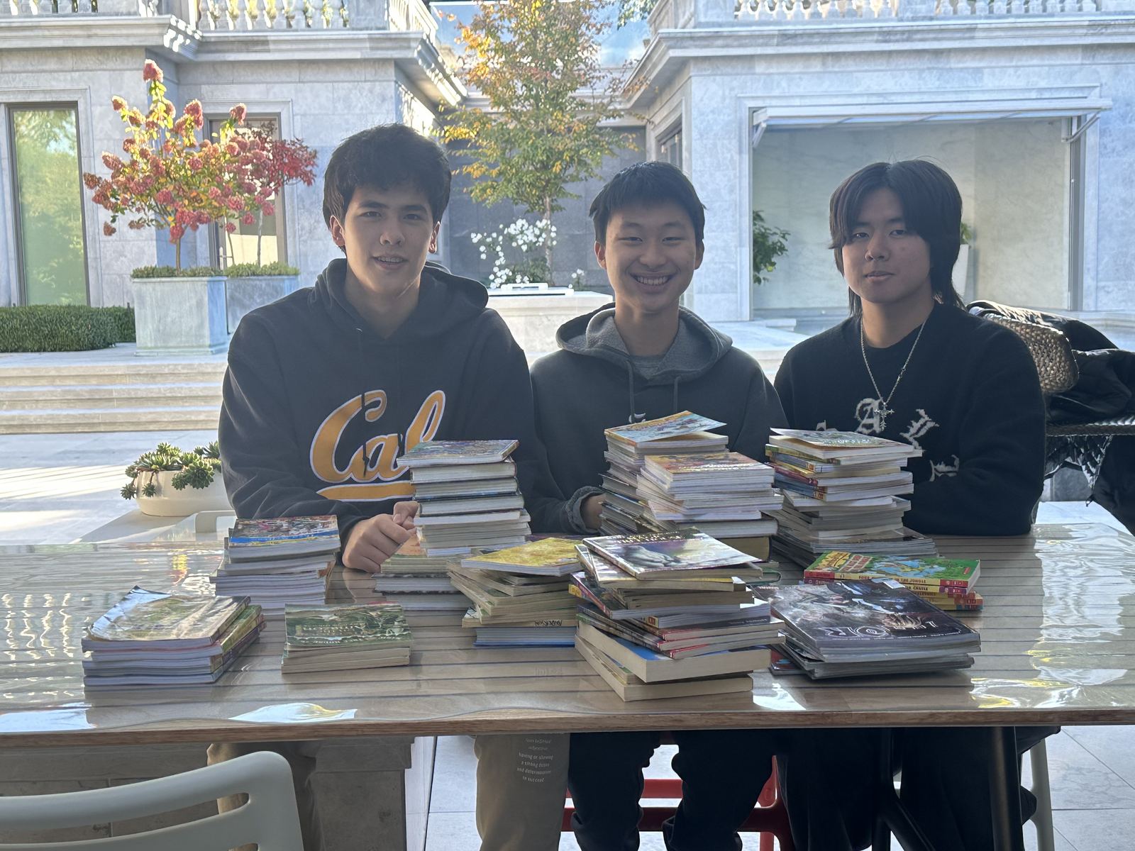Three student volunteers with stacks of collected books